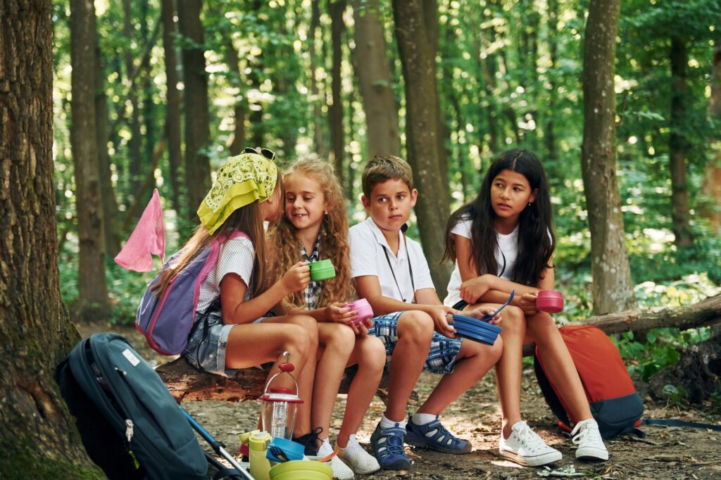 Sitting in the camp. Kids strolling in the forest with travel equipment